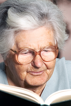 older woman reading a book with glasses