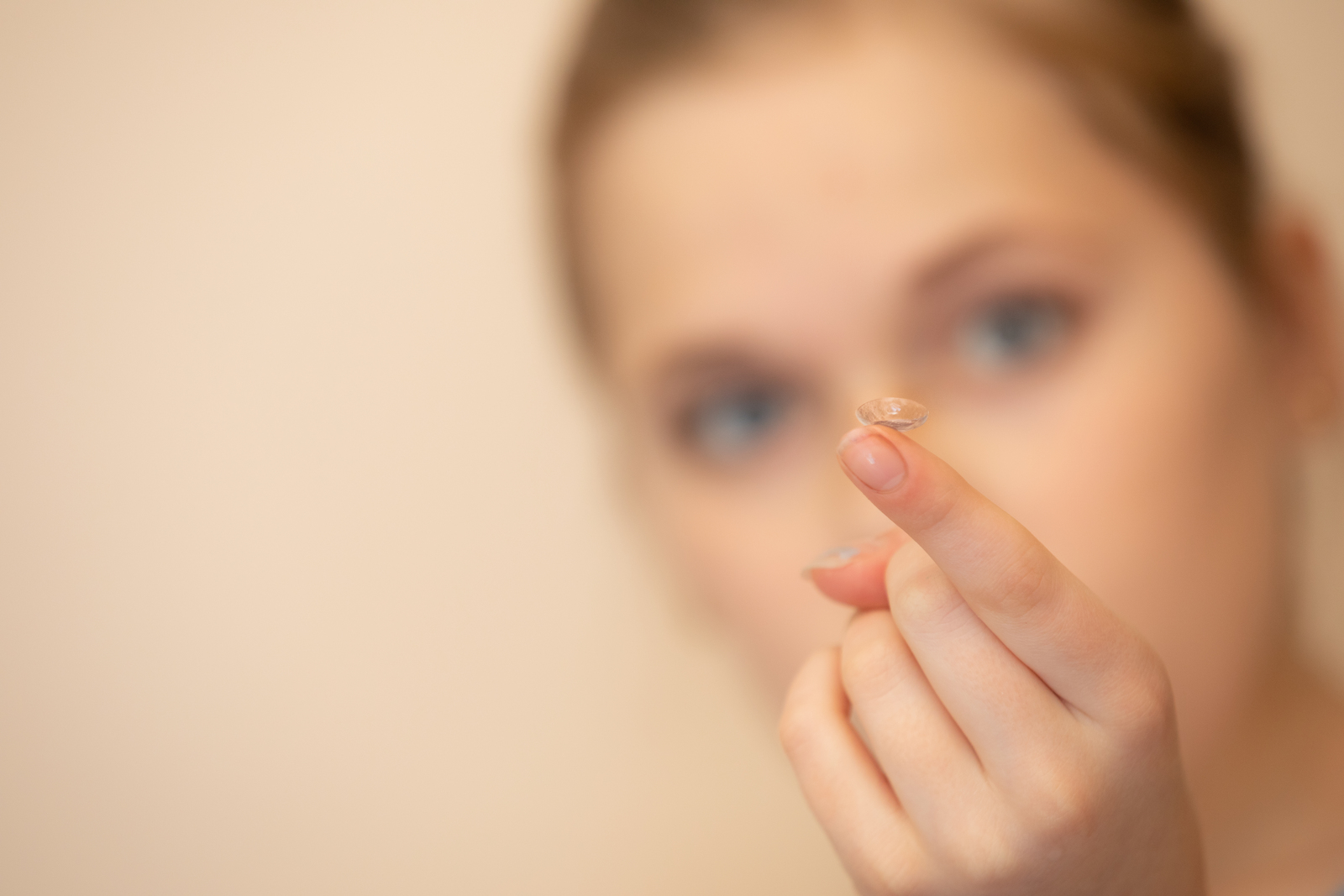 girl with contact on finger hand in finger are in focus, but head of girl is out of focus simulating myopia